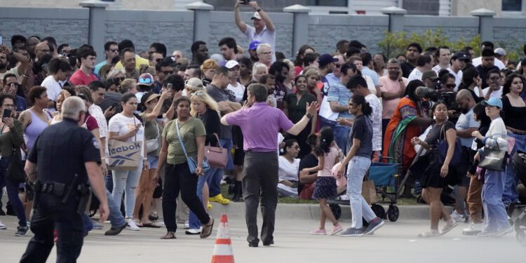 People gather across the street from a shopping center after a shooting Saturday, May 6, 2023, in Allen, Texas. (AP Photo/LM Otero)