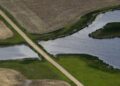 FILE - A road bisects a wetland on June 20, 2019, near Kulm, N.D. The Supreme Court has made it harder for the federal government to police water pollution. The decision from the court on Thursday, May 25, 2023, strips protections from wetlands that are isolated from larger bodies of water. It’s the second ruling in as many years in which a conservative majority has narrowed the reach of environmental regulations. (AP Photo/Charlie Riedel, File)