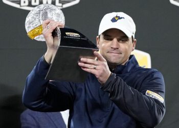 FILE - West Virginia head coach Neal Brown gets holds the trophy after their win against North Carolina in an NCAA college football game at the Duke's Mayo Bowl Wednesday, Dec. 27, 2023, in Charlotte, N.C. Brown has agreed to a $400,000 pay cut over the next three years while being rewarded with a one-year contract extension through 2027 following a nine-win season. (AP Photo/Chris Carlson, File)