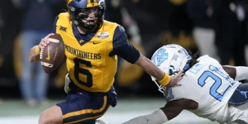 West Virginia quarterback Garrett Greene runs past North
Carolina defensive back Kaleb Cost during the first half of an NCAA college football game at the Duke's Mayo Bowl, Dec. 27, 2023, in Charlotte, N.C. (AP Photo/Chris Carlson, File)