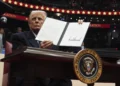 President Donald Trump signs an executive order as he attends an indoor Presidential Inauguration parade event at Capital One Arena, Monday, Jan. 20, 2025, in Washington. (AP Photo/Evan Vucci)